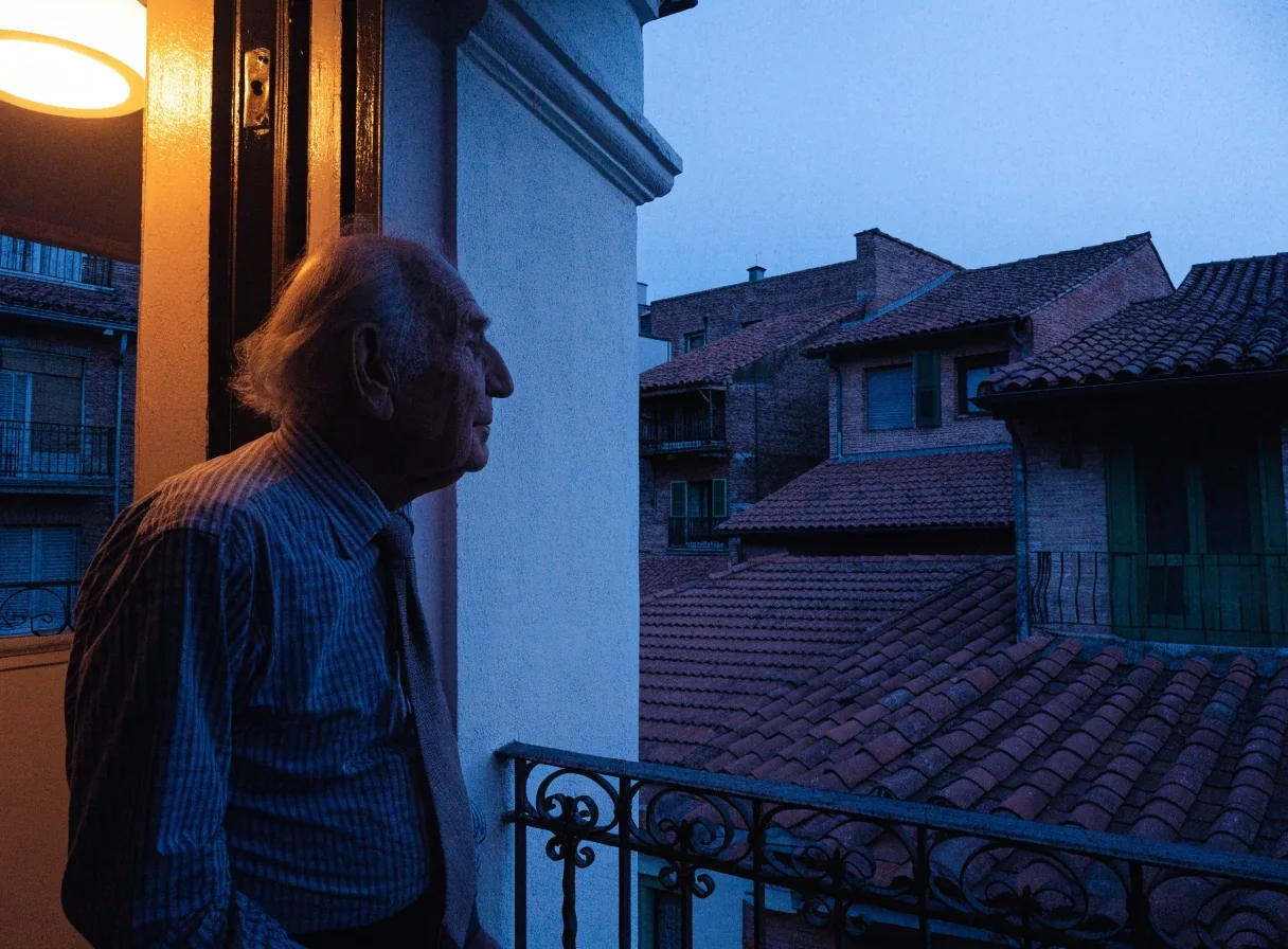 Fachada de un edificio español al atardecer con una ventana encendida